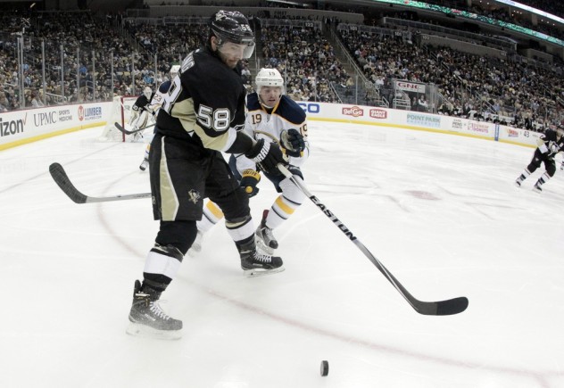 Mar 29, 2016; Pittsburgh, PA, USA; Pittsburgh Penguins defenseman Kris Letang (58) attempts to clear the puck in front of Buffalo Sabres center Cal O'Reilly (19) during the third period at the CONSOL Energy Center. The Penguins won 5-4 in a shootout. Mandatory Credit: Charles LeClaire-USA TODAY Sports